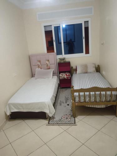 a bedroom with two beds and a window at Appart hôtel tanger in Oulad Akkou