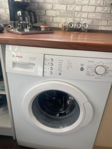 a white washing machine under a counter in a kitchen at La Ptite maison du Canal in Drevant