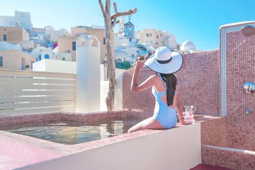 une femme en robe bleue et chapeau assise sur un livre dans l'établissement Luxury Villa Hariton, à Emporio