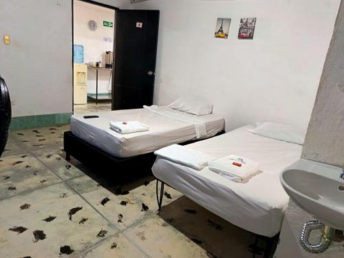 two beds in a room with a sink and a mirror at Hotel Efata in Apartadó