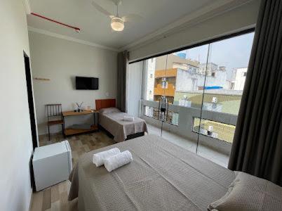 ein Schlafzimmer mit zwei Betten und einem großen Fenster in der Unterkunft Hotel Carmelita in Aparecida