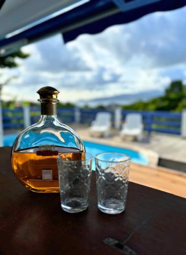 a bottle of whiskey and two glasses on a table at Les Terrasses de la Wallon Paprika in Les Trois-Îlets