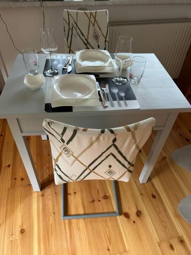 a white table with a chair with glasses on it at Gästehaus Kütt in Wörschach