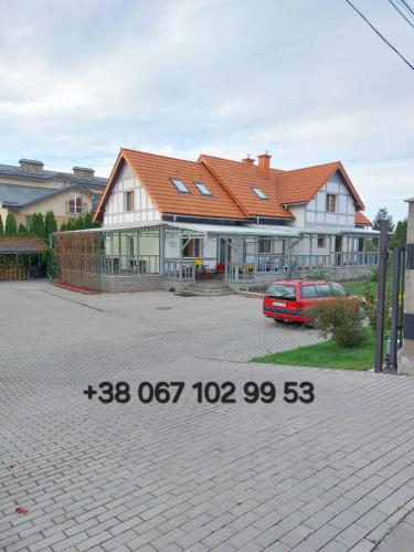 una casa con un coche aparcado delante en Пансіон АГАВА, en Novovolynsʼk