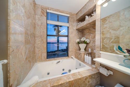La grande salle de bains est pourvue d'une baignoire et d'une fenêtre. dans l'établissement Ocean Vista Penthouse 2, à San Diego