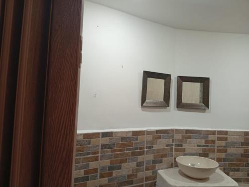 a bathroom with a toilet and two pictures on the wall at Alojamiento Independiente vipasa in Cali