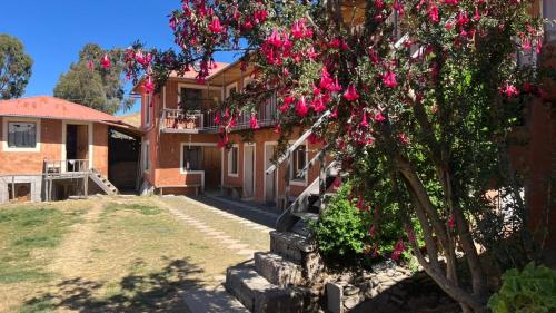 a house with a tree with pink flowers on it at Titicaca Lodge Amantani in Amantani