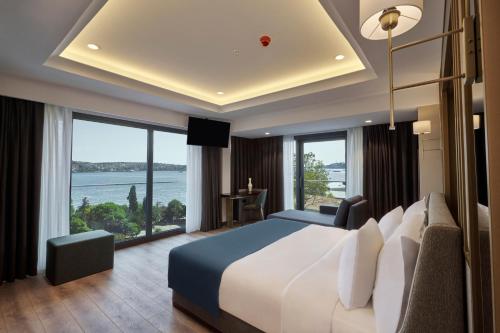 Un dormitorio con una cama grande y grandes ventanales. en Çırağan Hotel Bosphorus, en Estambul