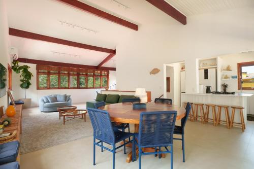 a dining room and living room with a wooden table and chairs at Casa Varanda Guaecá Pet Friendly, Heated Pool in São Sebastião