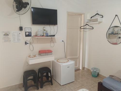 a living room with two stools and a tv on the wall at Suíte separada da casa principal in São Pedro