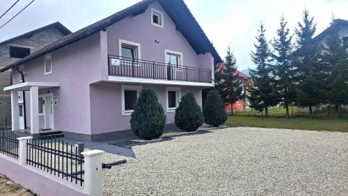 a pink house with a balcony and a driveway at Apartmani Biser Kupresa 2 in Kupres