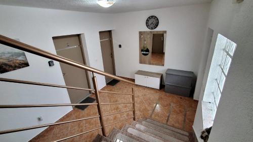 a room with a staircase with a couch and a clock at Apartmani Biser Kupresa 2 in Kupres