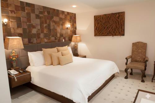 a bedroom with a large white bed and a chair at Casa Diamante Hotel Boutique - Mineral de Pozos in Mineral de Pozos
