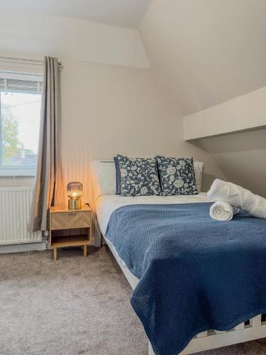 a bedroom with a bed with a blue blanket and a window at Middleton Mews- 3BR- Wollaton Park-Hospital & Uni in Nottingham