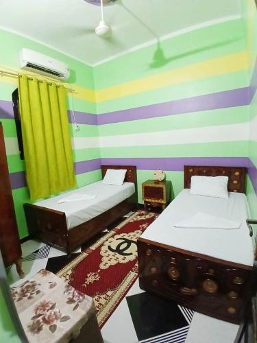 Una habitación con dos camas y una pared de rayas de colores. en Hamada guest house, en Asuán