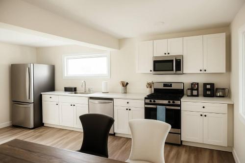 a kitchen with white cabinets and stainless steel appliances at Hot-tub, Games Room, Walk-in Sauna, 7 BM, 15 mins to Waterton in Mountain View