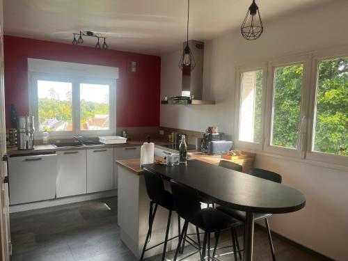 a kitchen with a table and some chairs in it at Maison de plain pied - 120m2 - Location cure ou vacances in Bagnoles de l'Orne