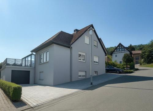 a white house with a garage in a driveway at Ella-ruhiges 3-Zimmer-Ferienapartment im Grünen mit Netflix, Koiteich und Terrasse 