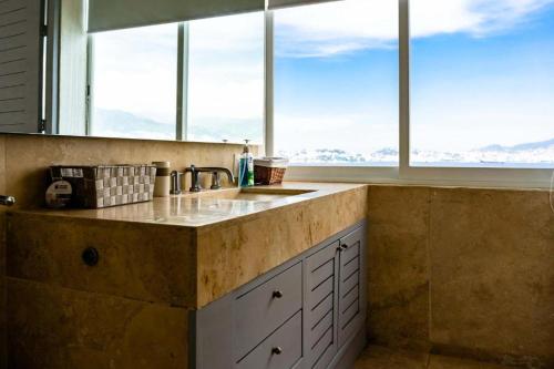 a kitchen with a counter with a sink and windows at Villa MAJUM Acapulco in Acapulco