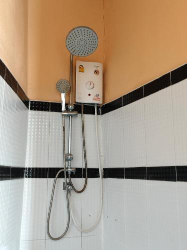 a shower in a bathroom with black and white tiles at Patcharin house in Ko Lanta Yai
