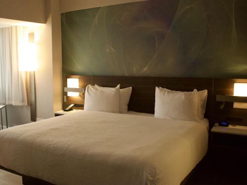 a bedroom with a large bed with a large painting on the wall at Armon Plaza Montreal Airport in Montréal