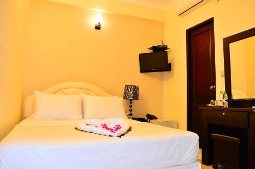 a bedroom with a white bed with a heart pillow on it at Beach Palace in Hulhumale