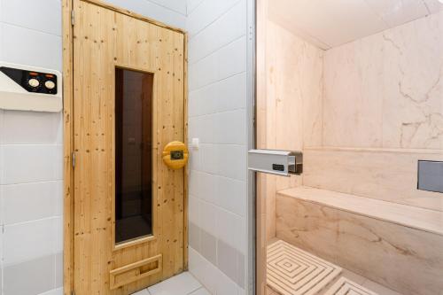 a bathroom with a shower with a wooden door at Hotel La Fontaine in Esmoriz