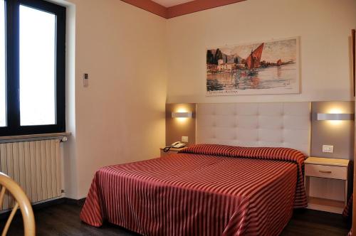 a bedroom with a bed with a red striped comforter at Hotel Panoramica in Salò