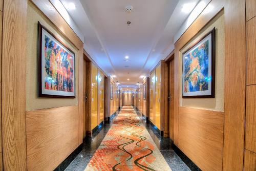 a hallway with paintings on the walls and a carpet at Best Western Summerlea in Jalandhar