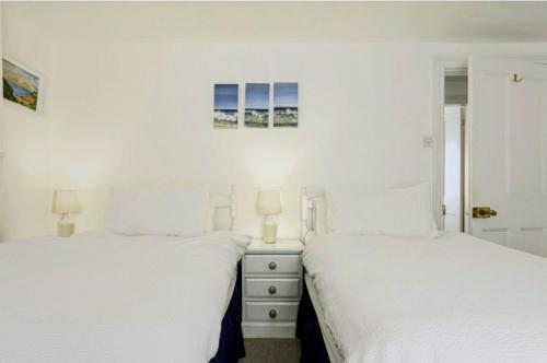two beds in a bedroom with white walls at Cozy, Bright Home Away From Home in Ballito