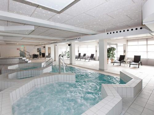a large swimming pool in a building with chairs at Blokhus Holiday Center in Blokhus