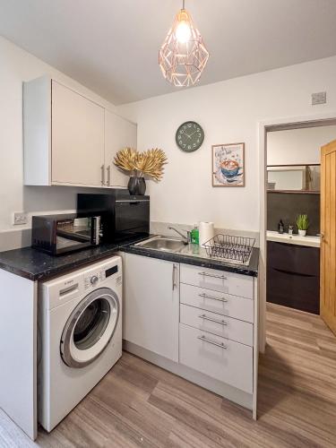 a kitchen with a washing machine and a microwave at Spacious 1 Bedroom City Center Flat in Derby in Derby