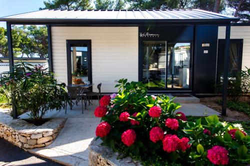 a house with red flowers in a garden at Waterman Beach Village in Supetar