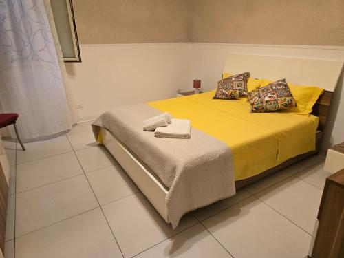 una camera da letto con un letto giallo e asciugamani di Tofus antiqua a Trapani