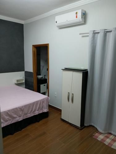 a bedroom with a bed and a refrigerator and a window at Casa Encanto in Franca
