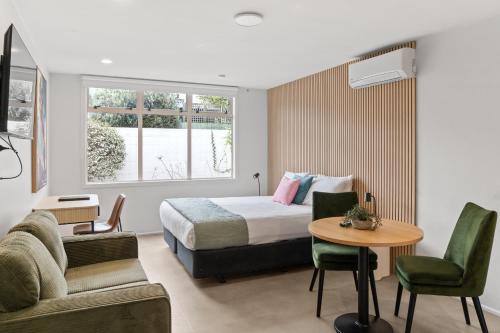 a hotel room with a bed and a table and chairs at Pacific Motor Inn in Mount Maunganui