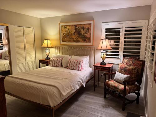 a bedroom with a bed and a chair and two lamps at Charming & Cozy 2-Bedroom in the Heart of Cathedral City! in Cathedral City