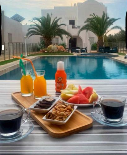 a tray of food and drinks on a table next to a pool at Menzel Yahia in Houmt Souk