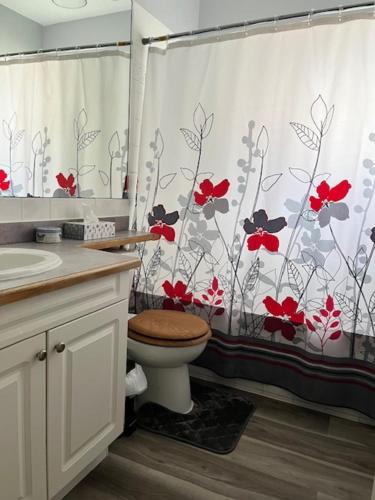 a bathroom with a toilet and a shower curtain with red flowers at Edgewood Road in North Vancouver