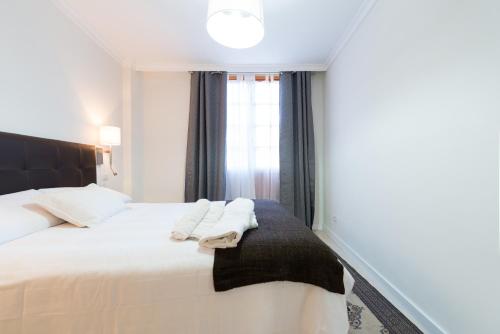a bedroom with a white bed with a black headboard and a window at Malfu Home in Las Palmas de Gran Canaria