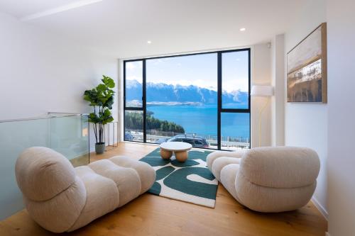 a living room with two chairs and a large window at The Alpine Lakeview Luxe Retreat in Queenstown