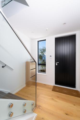 a staircase with a black door in a white room at The Alpine Lakeview Luxe Retreat in Queenstown