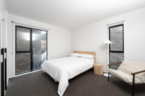 a white bedroom with a bed and a window at The Alpine Lakeview Luxe Retreat in Queenstown