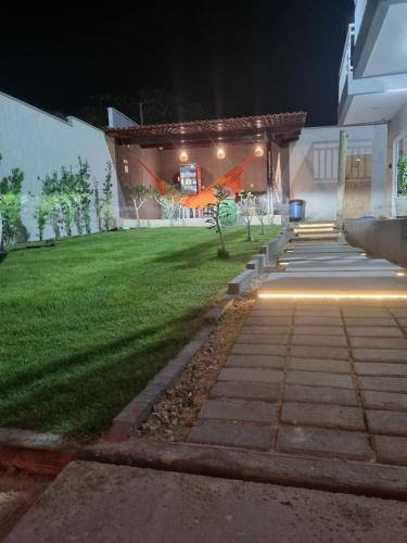 a house with a lawn with a building with lights at Residencial New Stilo-Coral in Aracati