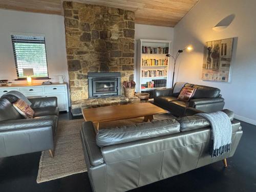 a living room with a leather couch and a fireplace at Valley Cottage, Treeton winery, Margaret River in Cowaramup