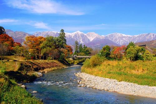a river with trees and mountains in the background at Kinagashi Happo Chalet East in Hakuba