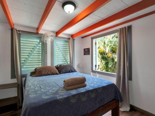 1 dormitorio con 1 cama con sábanas azules y 2 ventanas en Casa Cumbia Apartments, en Puerto Viejo