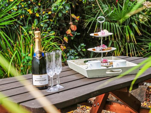 a bottle of champagne and glasses on a wooden table at Captain's House in Morfa Nefyn