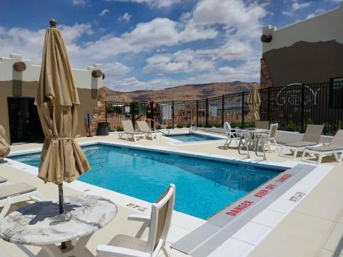 a swimming pool with chairs and a umbrella at Adventure Base #2 by Lake Powell in Big Water