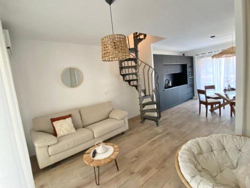 a living room with a couch and a spiral staircase at Joli mas bohème 60 m carré a seulement une minute à pied de la plage 4 personnes in Le Pradet